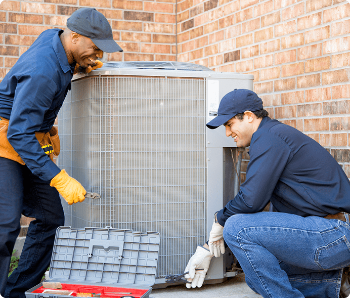 Two technicians repairing an outdoor air conditioning unit.